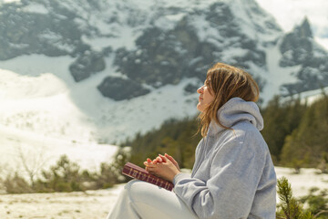 A girl in the mountains sits on a stone and reads the Bible. A girl with a Bible in her hands prays and spends time with God. Spiritual growth.