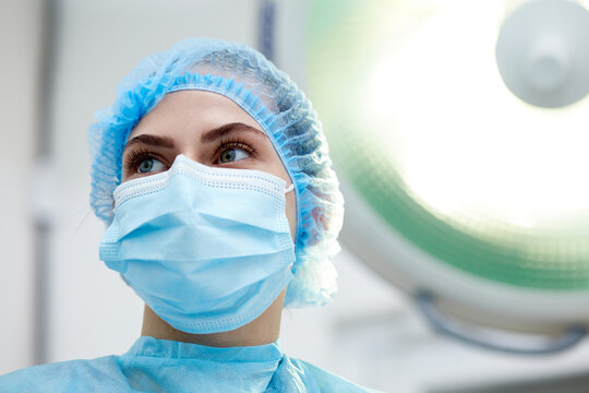 Close-up image of young woman, doctor, surgeon in protective medical mask leading surgery in medical clinic, hospital in surgery room. Concept of medicine, hospital, healthcare, treatment, profession