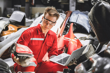 Old used car part warehouse worker checking inventory in garage. Staff worker working in recycle motor junkyard auto parts management.