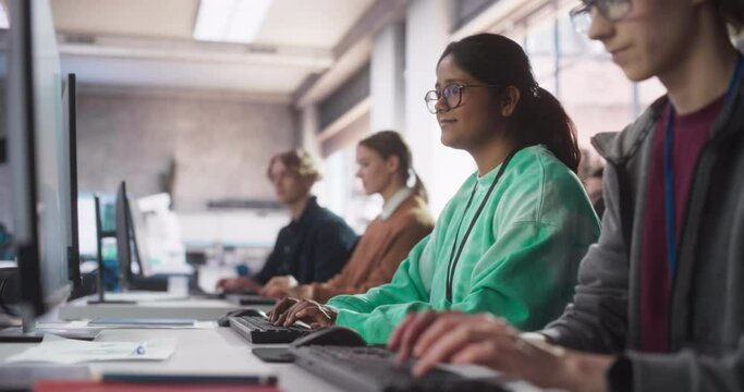 Inspired South Asian Female Student Studying in College with Diverse Multiethnic Classmates. Indian Girl Listening to Teacher, Using Computer to Apply Her Knowledge to Acquire New IT Skills in Class