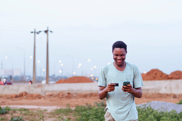 happy african man using credit card and mobile phone device for shopping online