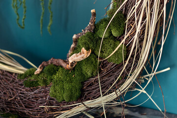 Close-up of home wall decor made of natural materials.A fragment of a wreath of twigs, driftwood,stabilized moss and leaves.Biophilia design concept.