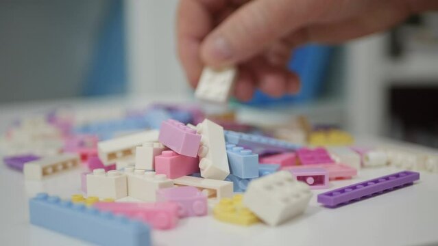 Blurred Shooting with an Elderly Person Playing Like a Child with Colorful Small Toy Bricks on the Table.