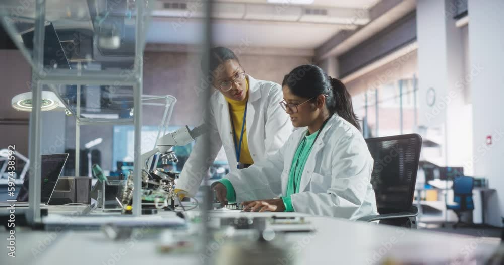 Poster Indian Girl Having a Conversation with a Mentor in a Laboratory, While Working on a Circuit Board for a Project. Young Scholar Talking with a Scientist About Changing the CPU Memory Characteristics