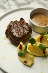 Beef stew and mashed potato with sauce on a white plate,