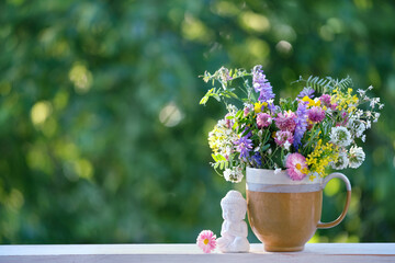 Buddha statue and meadow flowers in cup on table, abstract green natural background. spring, summer season. esoteric spiritual practice for harmony, meditation. Relax time. life balance concept