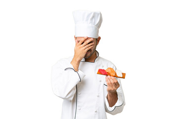 Young caucasian chef holding a sushi over isolated background with tired and sick expression