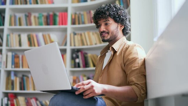 Close up of young student using, typing on laptop computer for online e-learning in campus library space. A handsome male is preparing for the examination period at the university in the classroom