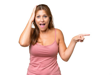 Middle-aged caucasian woman over isolated background surprised and pointing finger to the side
