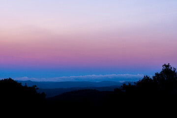 Blue and pink sunset with clear sky and silhouette of forest