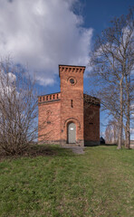 Fototapeta na wymiar Old red brick water tower on the island Skeppsholmen, a sunny spring day with cumulus clouds in Stockholm