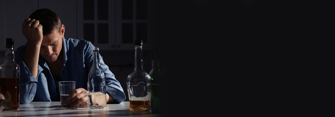 Suffering from hangover. Man with alcoholic drink at table in kitchen, space for text. Banner design