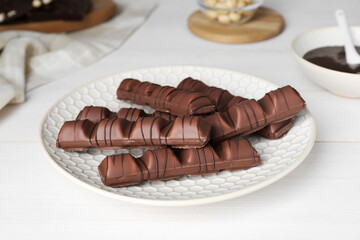 Tasty chocolate bars on white wooden table