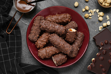 Tasty chocolate bars with caramel and nuts on light grey table, flat lay