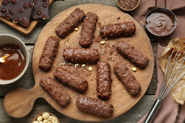 Tasty chocolate bars with caramel and nuts on wooden table, flat lay