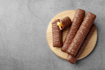 Sweet tasty chocolate bars with caramel on grey table, top view. Space for text