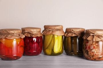 Jars with different preserved vegetables on wooden table