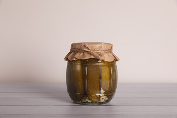 Jar with pickled cucumbers on white wooden table