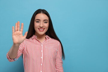 Happy woman giving high five on light blue background, space for text