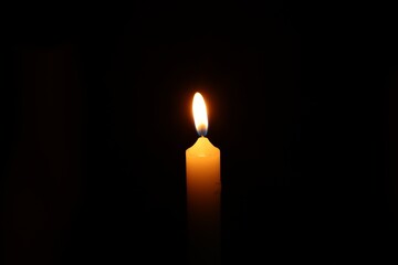 One burning wax candle on black background
