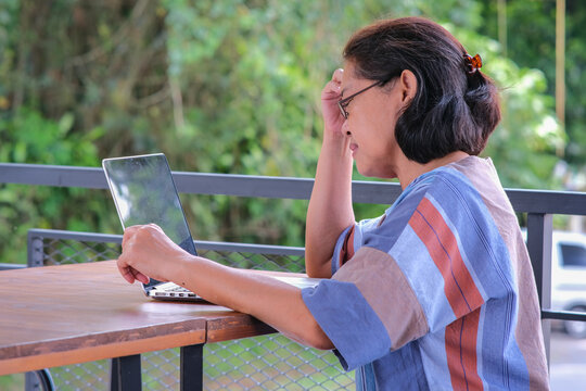 Side view: A middle-aged woman is working on her laptop