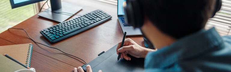 Back view of man designer in headphones works in home office. High quality photo