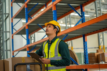 Warehouse employees reading a clipboard in a logistics centre,Warehouse worker taking packages for shipment in a large distribution centre.