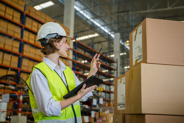 Logistics worker storing package boxes in a large distribution centre,Warehouse worker moving cardboard boxes while working with a colleague in a warehouse,.