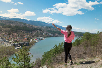 Woman standing  in the mountain high above a blue lake with stunning panoramic view .Traveling in the nature in Bulgaria 