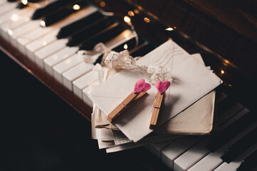 Paper snail mail letters and envelopes with heart pins on piano keys closeup top view. Love and romance concept. Valentines Day.