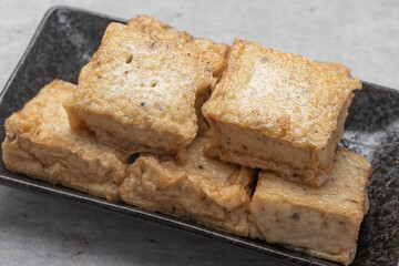 Fried black sesame tofu in a black plate