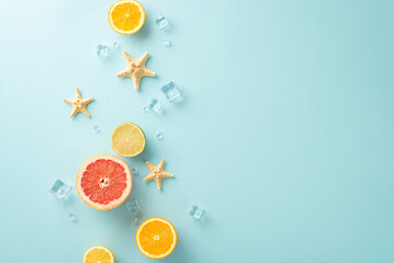 Create unforgettable summer memories with colorful citrus fruit, ice cubes and starfish. Top view flat lay on blue background with copyspace for text or advert