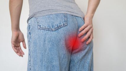 Caucasian woman suffering from hemorrhoids. The faceless girl keeps her hands on the pope.