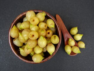 Madhuca longifolia or Mahua in a wooden bowl on black background  top view 