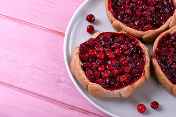 Kalitka pie, Karelian pasty, with cowberry on pink table. Closeup - obrazy, fototapety, plakaty