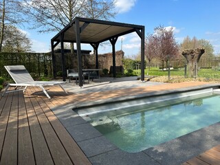 Swimming pool. Modern terrace with pool, aluminum pergola and deck chair. Wooden decking
