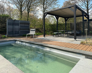 Swimming pool. Modern terrace with pool, aluminum pergola and deck chair. Wooden decking