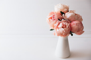 Beautiful bouquet of fresh coral peony flowers in full bloom in vase. Floral still life with blooming peonies. Negative space for text. © Iryna