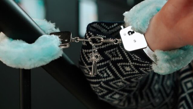 Close-up of fluffy handcuffs with a key on a girl's hand in an adult sex shop for romantic sensations