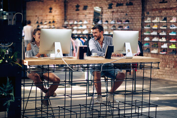 Young man and woman in store working on their pc, and laughing.