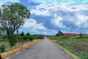 Fototapeta na wymiar Carretera en el campo con cielo azul y nubes blancas