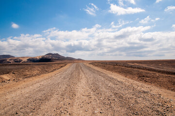 Fototapeta na wymiar View of a road in a volcanic desert area in Fuerteventura, Canary Islands.