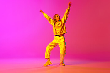 Portrait with one young girl, dancer with dreadlocks dancing with hands up over gradient pink background in neon light