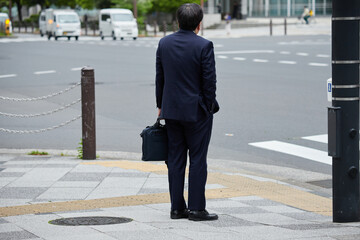 朝の交差点で信号待ちの一人のサラリーマン