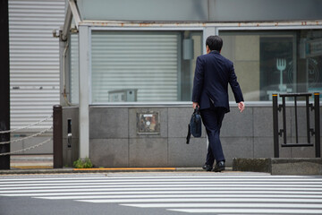 朝の交差点の横断歩道を渡る通勤する男性サラリーマン