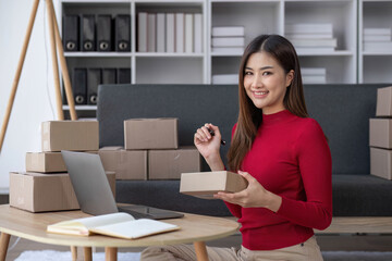 Startup small business entrepreneur SME, asian woman packing cloth in box. Portrait young Asian small business owner home office, online sell marketing delivery, SME e-commerce telemarketing concept.