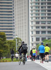 東京の皇居の前の道路で走るランナーたちの姿とオフィスビルの風景