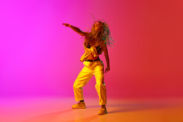 One professional hip-hop dancer wearing fashion clothes moving with inspiration over gradient pink...