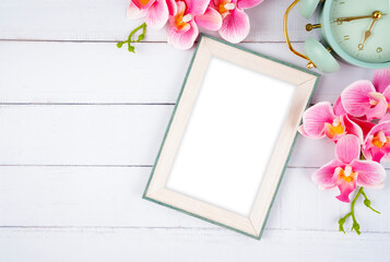 The Top view of blank photo frame and vintage alarm clock with pink color flower on wooden background, Save clipping path.