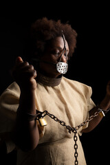 Portrait of a black woman wearing an iron mask on her face to represent the pain of the slave...